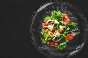 Salad with cucumber, tomato, red onion, pepper, parsley and Feta cheese on black background