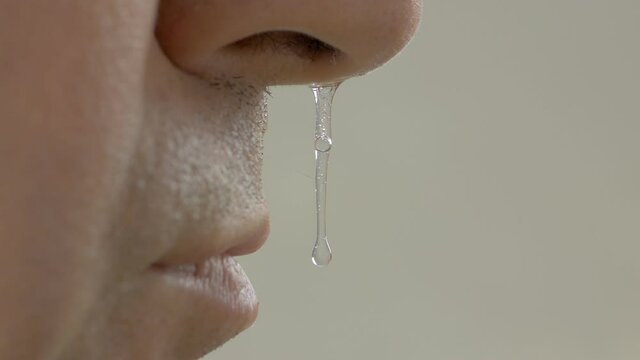 Close-up of an adult man's face with drooping snot from his nose