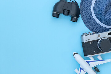 The traveling blue background with accessories for journey - hat, camera, binoculars and airplane