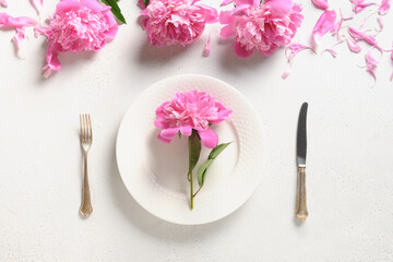 Fototapeta na wymiar Festive spring table setting with pink peony flowers on a white table. View from above. Banquet Invitation.
