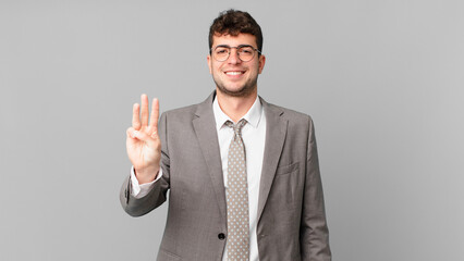 businessman smiling and looking friendly, showing number three or third with hand forward, counting...