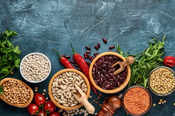 Legumes, lentils, chickpea, beans assortment, tasty appetizing ingredients spices grocery for cooking healthy kitchen on blue table. Weight loss diet and fight against cholesterol concept. Top view.