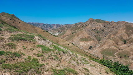 Fototapeta na wymiar A panoramic view on Daqing mountains in Inner Mongolia. Endless mountain chains. The slopes are mostly barren, overgrown with small bushes and grass. Desolated landscape. Bio diversity of a region