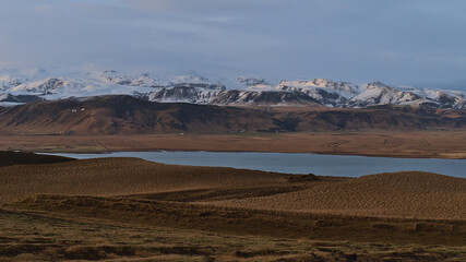 Beautiful panoramic view of the snow-capped foothills of ice cap Mýrdalsjökull, covering volcano Katla, in the evening light viewed from Dyrhólaey peninsula on the southern coast of Iceland.