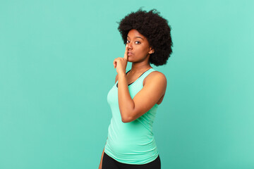 black afro woman asking for silence and quiet, gesturing with finger in front of mouth, saying shh or keeping a secret