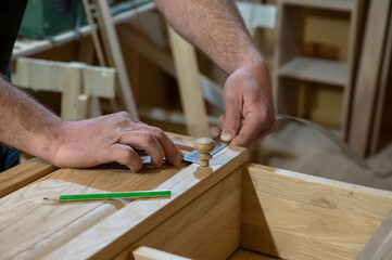 the hands of a master carpenter measure the distance with a pencil and a ruler. Handmade cabinet Production of wooden furniture. Selective focus