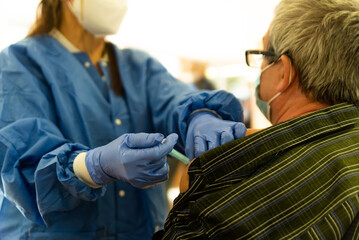 Barcelona, Spain - 4 april 2021: a nurse with syringe giving covid19 or coronavirus vaccine in clinic to a senior person. vaccination campaign and jab injection is under way all over spain - obrazy, fototapety, plakaty