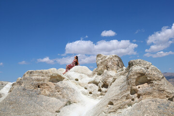 young  woman with long hair sitting on white stones