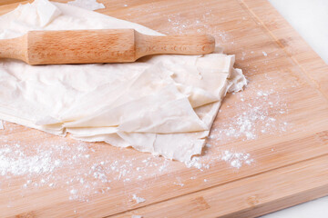 Filo dough and rolling pin on the wooden board 