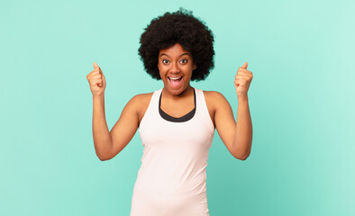 black afro woman feeling happy, positive and successful, celebrating victory, achievements or good...