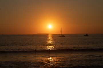 sunset on the beach with the silhouette of a boat