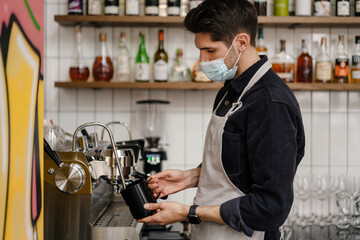 Young white brunette man in apron and protective mask