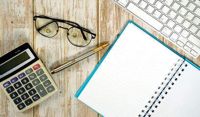 Workspace for working, wooden white table with keyboard calculator glasses and supplies. Flat lay composition. Top view, copy space.