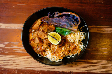 Red cabbage stewed with pork and egg noodles. Pan-Asian oriental cuisine on wooden table.