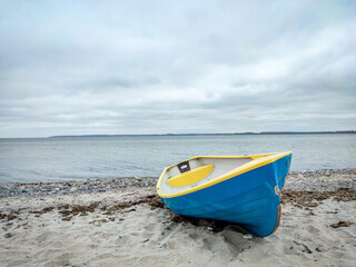 Photo of fishing boat on white sand beach at cloudy weathr in north Germany