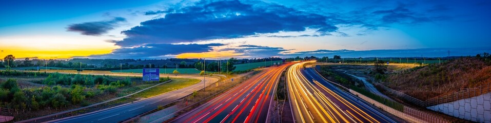 Colorful sunset at M1 motorway near Flitwick junction with cars light trails. United Kingdom - obrazy, fototapety, plakaty