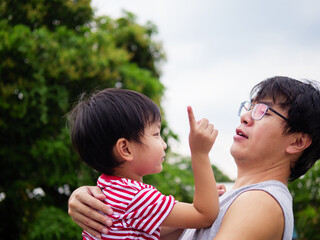 Obraz premium Asian cute child boy in hug of father in happy and funny moment shot. Kid smiling with happy cute face outdoor.Concept of father's day, relationship.