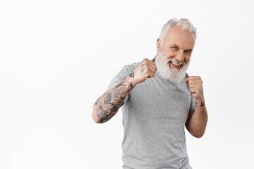 Look at my jab. Smiling playful senior man wants sparring, standing in boxing boxer pose and ready...