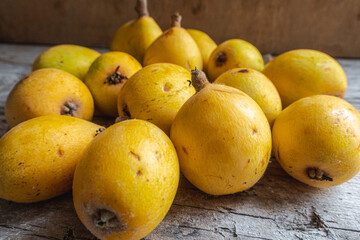 Group of sun-ripened organic loquats on top of a wooden board.