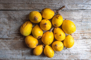 Group of sun-ripened organic loquats on top of a wooden board.
