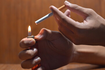 the gesture of a male hand holding a cigarette against a wooden background