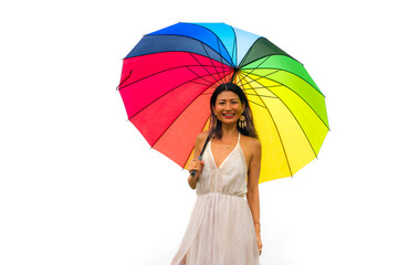 attractive and happy Asian woman holding rainbow colorful umbrella or parasol  smiling playful isolated on white background in beauty and freedom concept