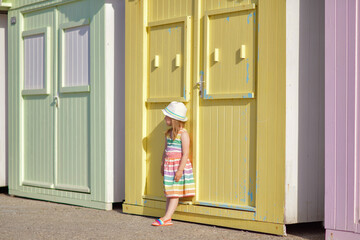 Girl in a colored dress near colorful wooden houses on the ocean Saint aubin sur mer
