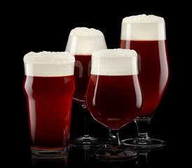 Set of fresh draft beer glasses with bubble froth isolated on black background.