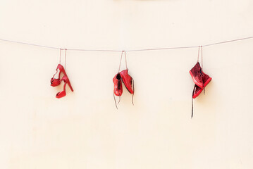 Three red shoes hanging by a thread.