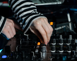 DJ presses a button on a mixing console, DJ equipment in front of him