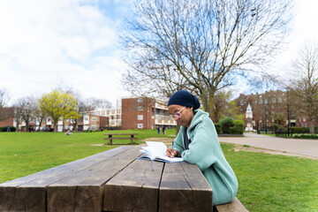 Fototapeta premium Black Muslim woman in park writing