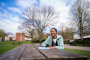 Fototapeta premium Black Muslim woman in park writing