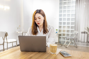 Pretty young asian business woman using laptop in modern cafe. 