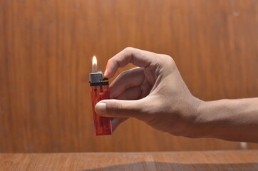 Hand Igniting Cigarette Lighter Against wooden Background