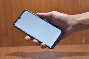 Close-Up Of Cropped Hand Holding Mobile Phone Against White Background