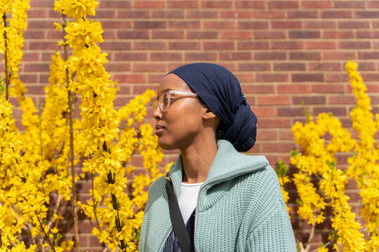Black Muslim woman next to yellow flowers