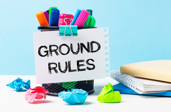 On a blue background - a stand with bright markers, notepads and multi-colored crumpled pieces of paper. A sheet of paper with the text GROUND RULES.