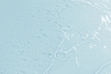 Abstract cosmetic background from transparent gel or antiseptic, hyaluron on blue background