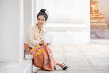 Thai woman in Thai dress resting in a temple After having used water soluble powder on cheeks for fun in celebrating Songkran water festival