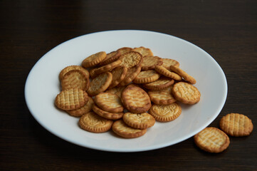 Small round dry cookies fon white plate close up