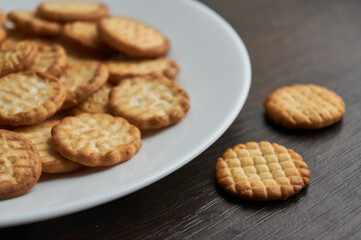 Small round dry cookies on white plate close up