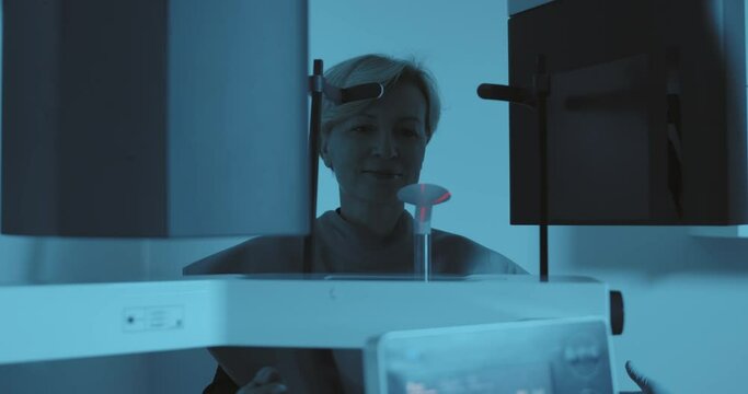 A female medical worker is inviting a female patient to scan in the 3D dental cone beam computerized tomography (CBCT).