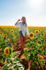 Mujer rubia con sombrero y gafas de sol en campo de girasoles