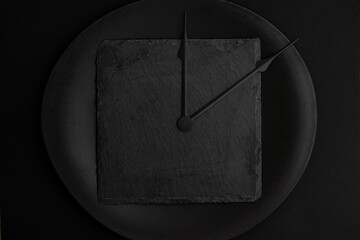 clock tongues  on a black ceramic plate, isolated on black. Different shades of black, creative concept.