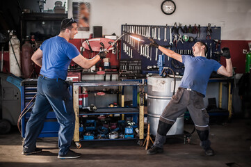 Funny workers. Car mechanic posing with their tools in workshop