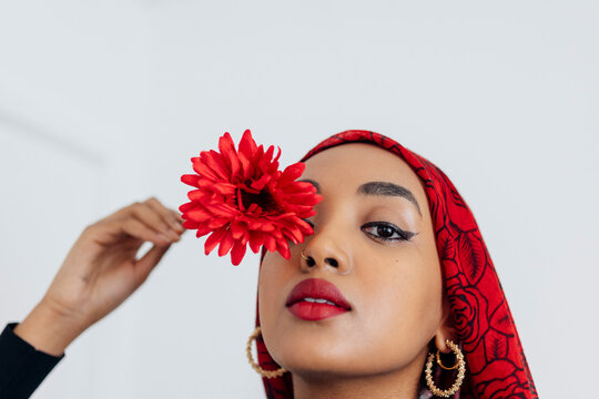 Black Muslim Woman wearing a red hijab with a red flower