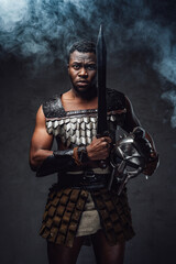 Fototapeta na wymiar Studio shot of fearful authentic gladiator of african descent with gladius