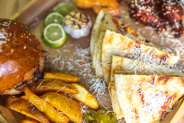 Food set of fried chicken wings, burger, fried potatoes, cheese, corn, sauce, salad