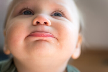 Looking up at the face of cute chubby toddler; bottom lip pushed out and eyes looking skyward