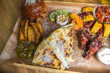 Food set of fried chicken wings, burger, fried potatoes, cheese, corn, sauce, salad